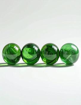 Four vibrant green glass spheres arranged in a horizontal row against a plain white background. Each sphere exhibits swirling, translucent patterns photo