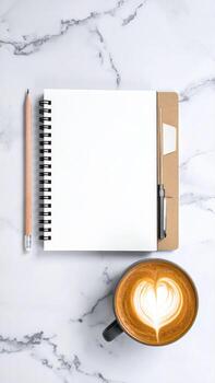 A blank notebook, pencil, pen, and latte on marble photo