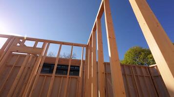 Wooden Beams and posts under clear sky on the construction development site. Construction frame of New House. Camera move. Bottom up view video