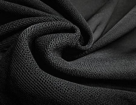 Close-up of black, textured fabric. Curved folds and a noticeable mesh pattern photo