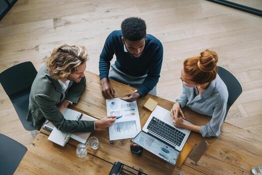Business meeting among diverse professionals discussing reports and strategies in a modern office setting photo