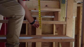 Construction worker measures with measurement tape the size of wooden stairs at Home Renovation, repair or construction process video