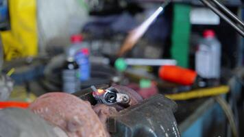 metallarbete i framsteg. en ficklampa flamma är applicerad till en cylindrisk metall objekt hölls i skruvstäd. de flamma glöder med hög tryck, föreslår svetsning, lödning, skärande. video