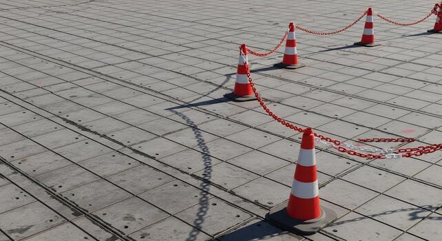 Traffic cones and barrier chain forming a curve within formwork panel grid, emphasizing ultrasharp textures and crisp edges. photo