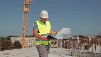 Construction Supervisor On Roof Holding Documents, Man In Hard Hat And Vest Overlooking Reinforcement Mesh And Surrounding Area On Clear Sunny Day video