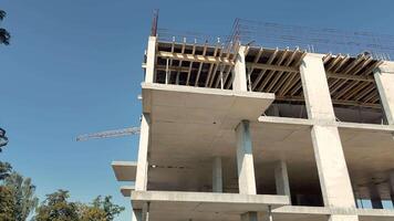 Low Angle View Of Unfinished Concrete Building Frame, Clear Blue Sky Background And Tower Crane Visible In The Distance video