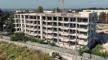 stänga upp se av oavslutat betong byggnad ram, arbetare på topp golv och torn kran Bakom, konstruktion framsteg av mång våning strukturera video