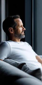 A man sitting on a couch looking out the window photo