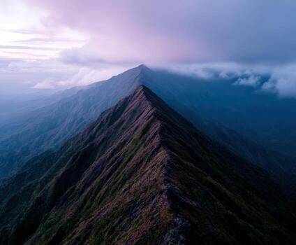 A mountain peak with clouds and a dark sky photo