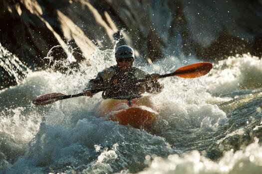 A man in a kayak riding through a wave photo