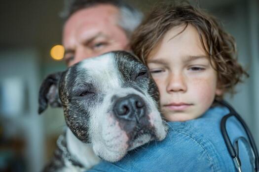 A man and a boy are hugging a dog photo