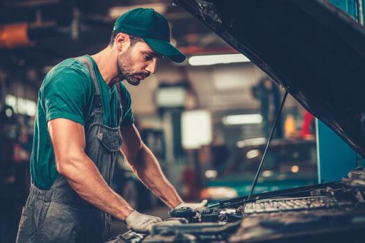 A man in an overalls working on a car photo