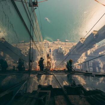 A man is working on a building in front of a large mirror photo