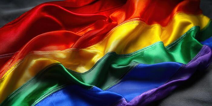 A close-up of a colorful rainbow pride flag made of silky fabric. photo