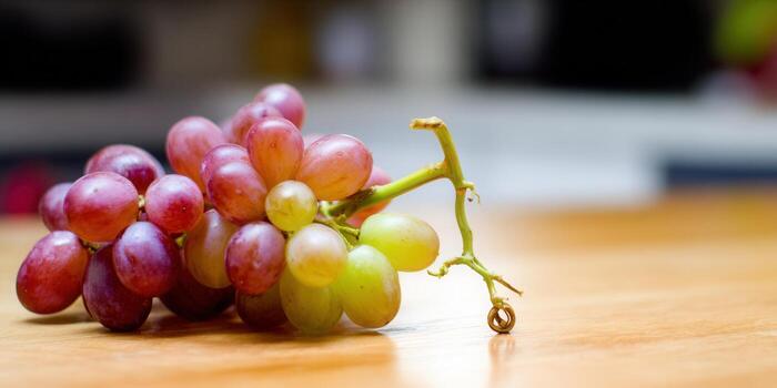 A beautiful cluster of red grapes rests gracefully on a wooden surface, ready to be enjoyed. photo