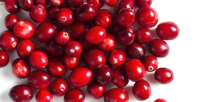 A close-up view showcases a pile of fresh, red cranberries against a white backdrop. photo