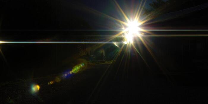 The sun bursts with brilliance, casting light and shadows on a dark path, creating a stunning visual photo