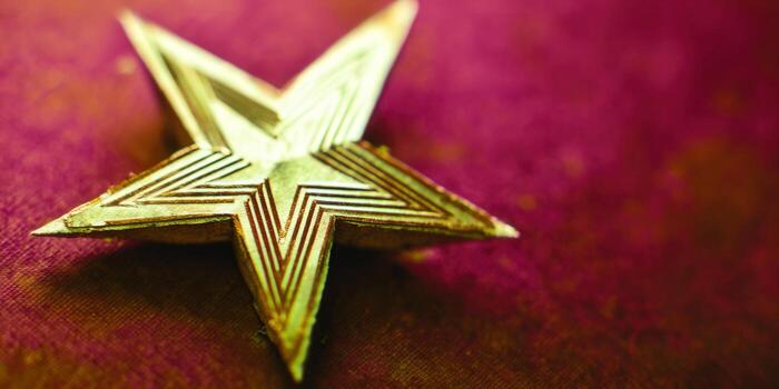 A stunning golden star stands out against a deep burgundy backdrop, creating an elegant contrast. photo