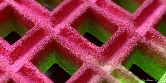 A vibrant close-up of a colorful waffle texture with striking pink and green hues. photo