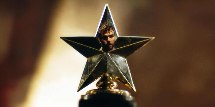 A man's face is positioned within a golden star-shaped trophy, signifying triumph and success. photo