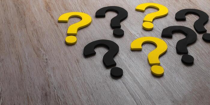 A collection of yellow and black question marks on a wood background, representing choices. photo