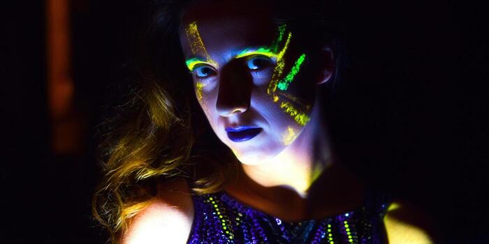 A woman's face is illuminated with neon paint, creating a striking and creative portrait. photo