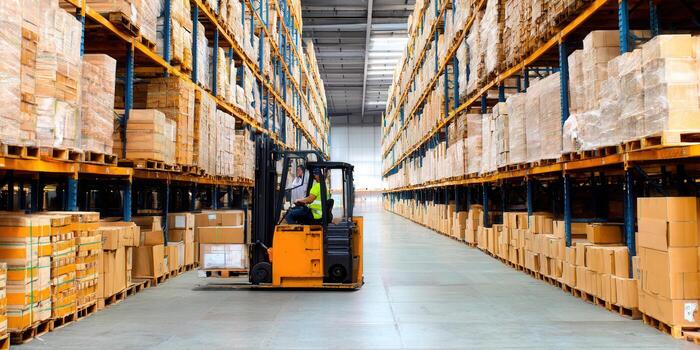 Inside of a spacious warehouse, with a forklift handling goods and boxes on the shelves. photo