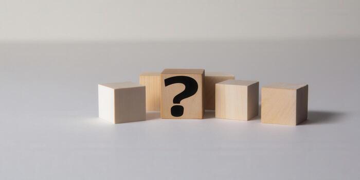 A wooden block with a black question mark is the main focus of the image. photo