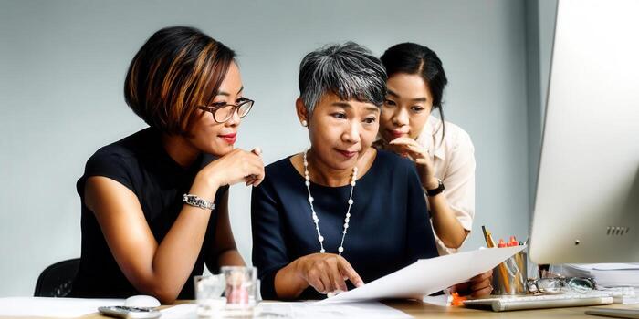 Businesswomen review documents at a desk, collaborating on a project. photo
