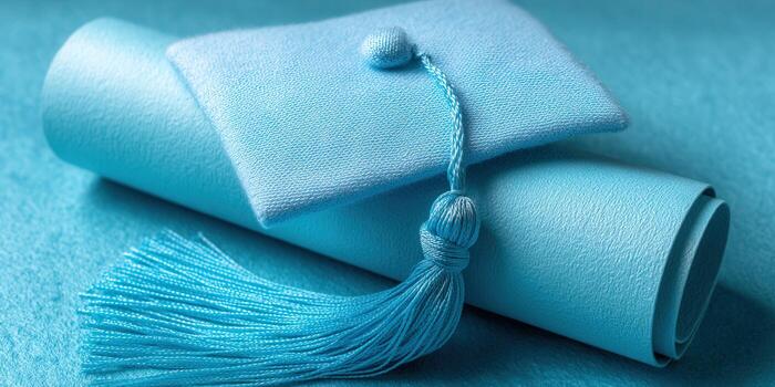 Light blue graduation cap and diploma on a textured background. photo