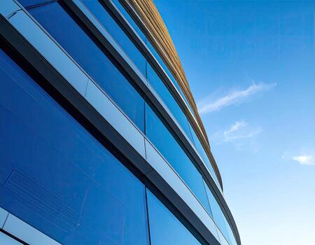 Modern building facade with curved glass windows against a clear blue sky photo