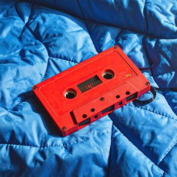 Red cassette tape on a blue quilted blanket photo