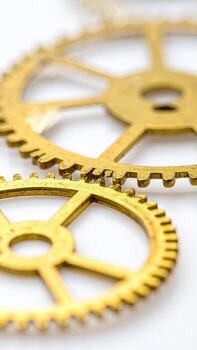 Close-up of interlocking gears, golden hue against white background photo