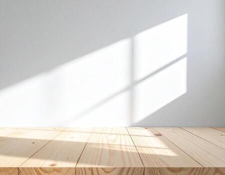 Sunlight streams through a window, casting shadows on a light-colored wooden surface against a plain wall photo
