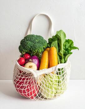 A white reusable mesh bag filled with fresh vegetables photo