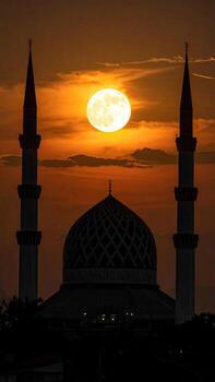 Silhouette of a mosque at sunset with a large moon photo