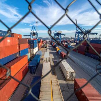 Shipping containers lined up behind a chain-link fence photo