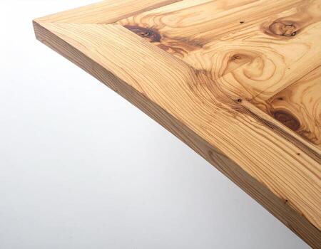 Close-up of a light-colored wooden table corner. The wood grain is visible, showing a natural pattern with subtle variations in color. A simple, rectangular frame outlines the tabletop. White background photo