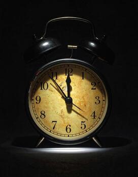 Vintage alarm clock, dark background, illuminated face photo