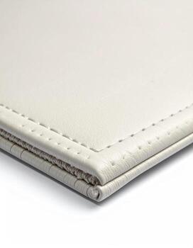 Close-up of a cream-colored leather-like folder or document protector, showing a stitched edge photo