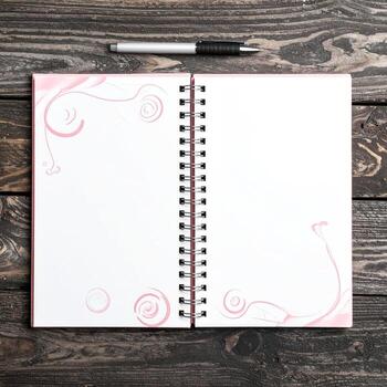Open spiral-bound notebook, light pink cover, blank pages, on dark wood photo