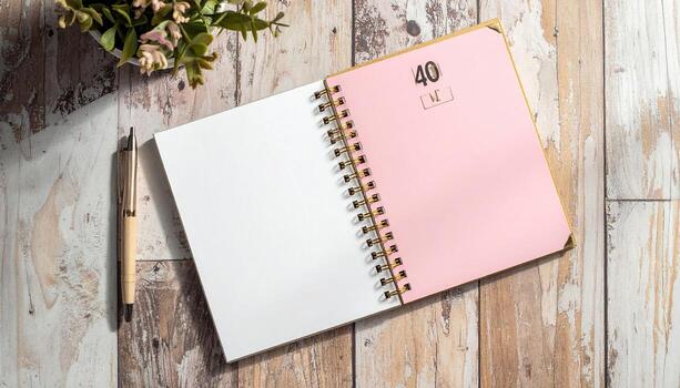 Open spiral-bound notebook with blank pages, pink cover, and wooden background photo