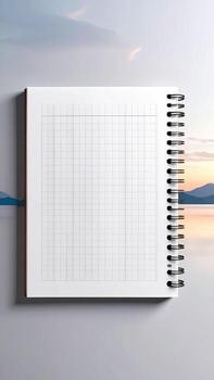 Open notebook with grid paper, set against a soft-focus backdrop of a tranquil lakeside sunrise photo
