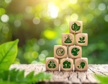 Wooden blocks with green environmental icons, stacked in a growth pattern, set on a rustic wooden surface amongst foliage photo