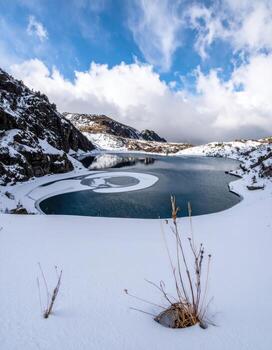 Snowy landscape overlooking a tranquil alpine lake with icy patterns photo