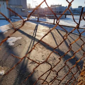A rusty chain link fence is seen in the sun photo