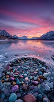 A colorful sunset over a lake with rocks and water photo