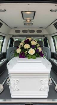 Interior view of a hearse with a white coffin adorned with flowers in the back compartment of the vehicle photo