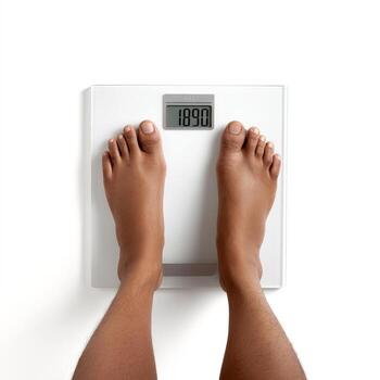 Person standing on a white digital scale displaying a weight reading on the screen. photo