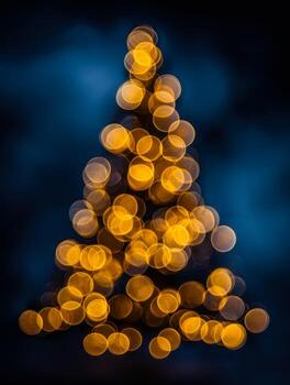 Soft glowing golden lights arranged in a triangular pattern resembling a festive holiday tree against a deep blue and black blurred background at night photo